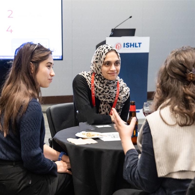 Photo of three early career members sitting around a table talking