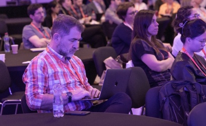 Man sitting in a crowded room looking at a computer
