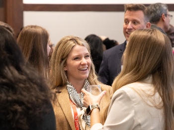 smiling woman surrounded by other people at ISHLT2025 Mentor Meetup Event