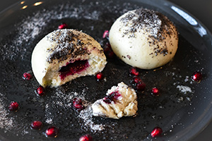 Two Czech pastries with a white exterior, red custard filling, and black seeds dusted on the top