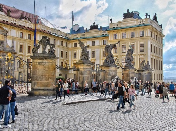 Photo of people walking down the street in front of a yellow building in Prague