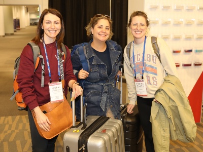 Photo of three women standing with suitcases