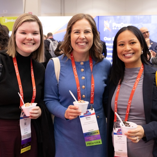 Three women smiling in the exhibit halll
