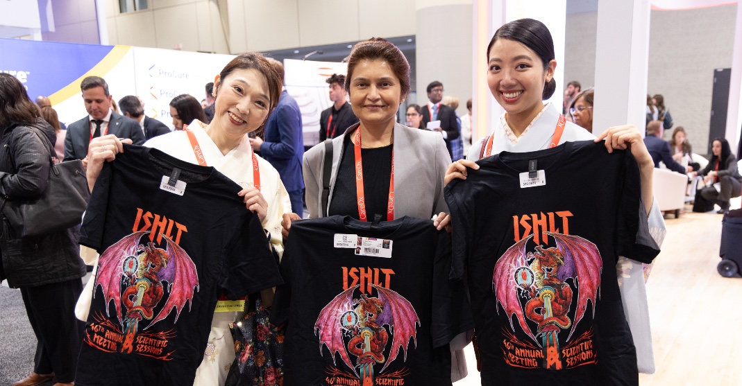 Photo of three women in the exhibit hall holding ISHLT2026 shirts