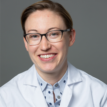 A headshot of Lauren Truby wearing glasses and a white lab coat against a grey background