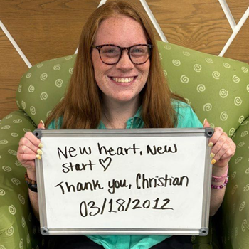 Payton-Herres-Patient-Photo Payton Herres holds a white board with the name of her heart transplant donor Christian