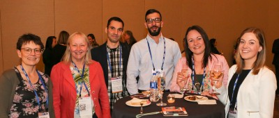 ISHLT members gathered around table smile for photo